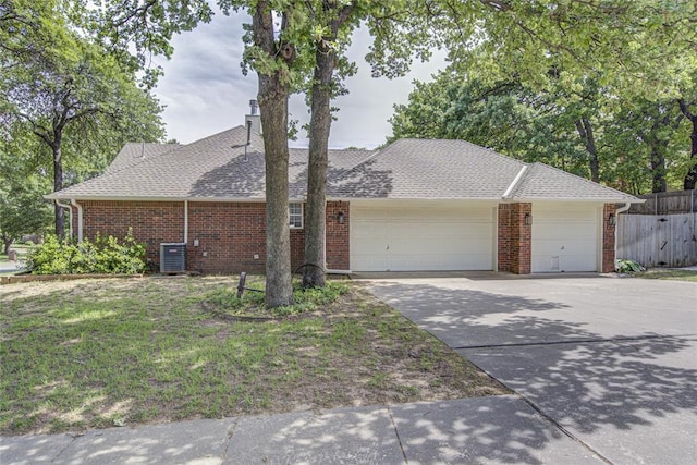 view of front of home featuring a garage, driveway, brick siding, a shingled roof, and cooling unit