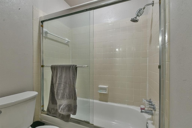 807 Cardinal Creek Blvd Unit C, Norman, OK 73072 - bathroom featuring a textured wall, bath / shower combo with glass door, and toilet