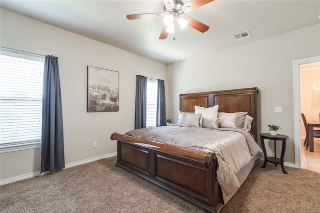 bedroom featuring light carpet, multiple windows, baseboards, and a ceiling fan