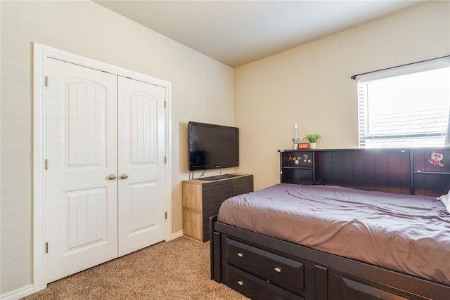 bedroom with light carpet, a closet, and baseboards