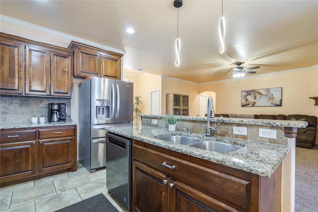 kitchen featuring appliances with stainless steel finishes, a sink, ornamental molding, a ceiling fan, and decorative light fixtures