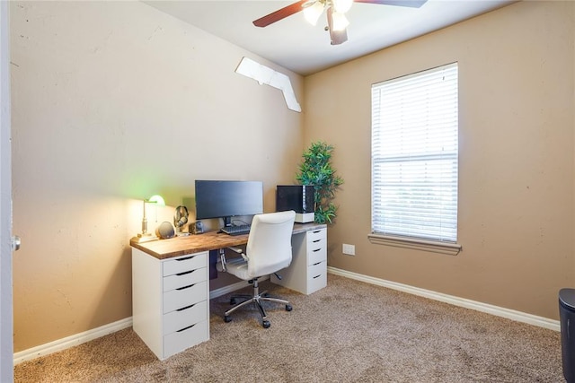 office space featuring light carpet, a ceiling fan, and baseboards