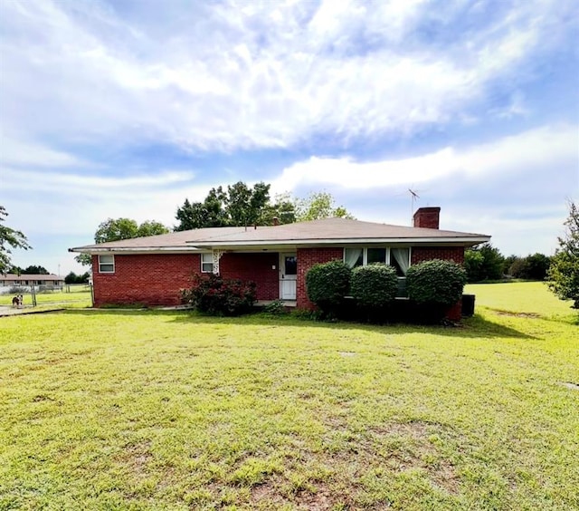 ranch-style house with a front yard, a chimney, and brick siding