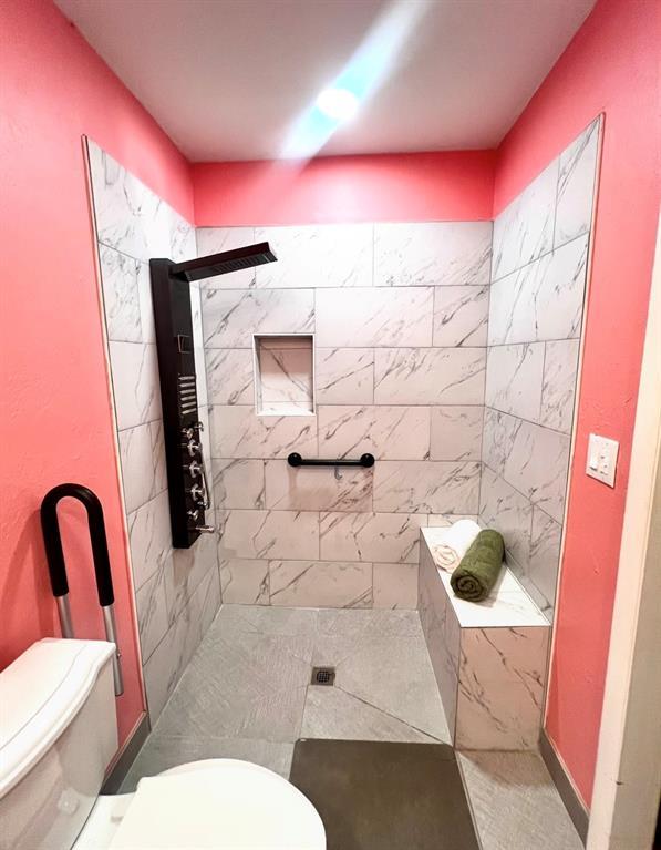full bath with toilet and tiled shower