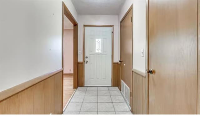 18906 13th St, Shawnee, OK 74801 - doorway to outside with wainscoting, light tile patterned floors, a textured ceiling, and wood walls