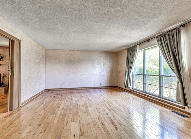 18906 13th St, Shawnee, OK 74801 - empty room featuring light wood-style flooring, a textured ceiling, baseboards, and a textured wall