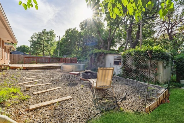 805 John F Kroutil Dr, Yukon, OK 73099 - view of yard with an outdoor fire pit, fence, a wooden deck, an outdoor structure, and a storage unit