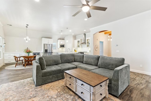 living room with ceiling fan, wood finished floors, crown molding, arched walkways, and baseboards