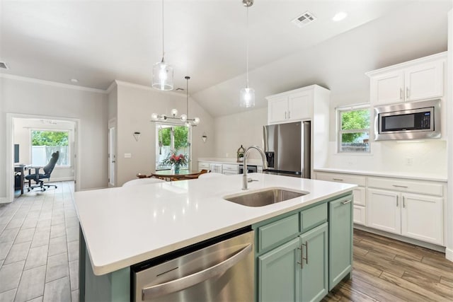 kitchen with appliances with stainless steel finishes, a sink, an island with sink, white cabinetry, and light countertops