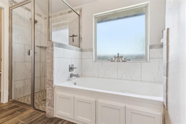full bath featuring a stall shower, a bath, and wood finished floors