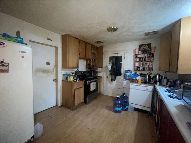 422 E Ash St, Lexington, OK 73051 - kitchen with white appliances, brown cabinetry, light wood-style floors, a textured ceiling, and light countertops
