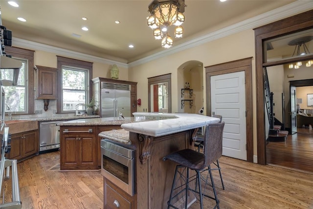 1415 N Hudson Ave, Oklahoma City, OK 73103 - kitchen featuring built in appliances, a center island, light wood-style floors, a breakfast bar, and crown molding