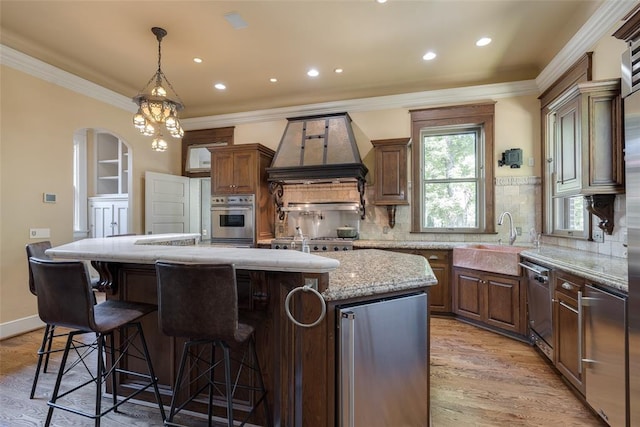 1415 N Hudson Ave, Oklahoma City, OK 73103 - kitchen featuring custom exhaust hood, appliances with stainless steel finishes, a sink, a center island, and light wood-style floors