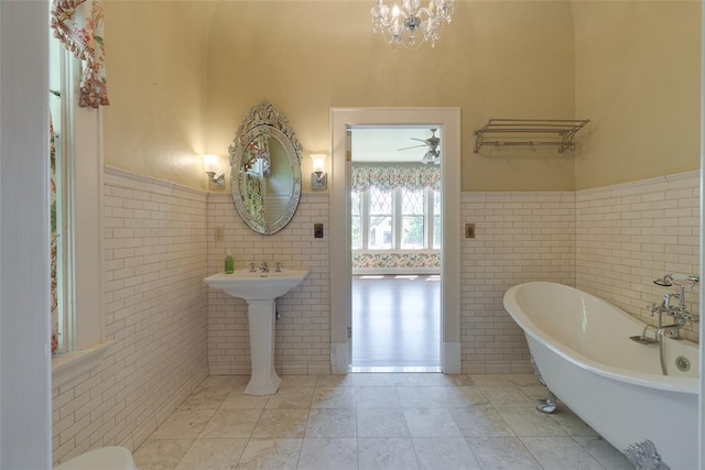 1415 N Hudson Ave, Oklahoma City, OK 73103 - full bathroom featuring tile walls, wainscoting, a soaking tub, tile patterned flooring, and a chandelier