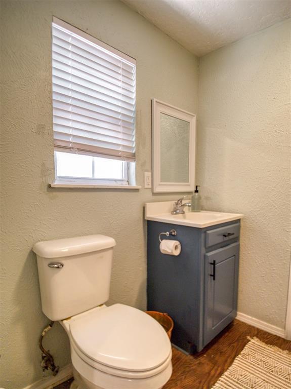 164 4th St, Faxon, OK 73540 - bathroom featuring wood finished floors, baseboards, toilet, and vanity