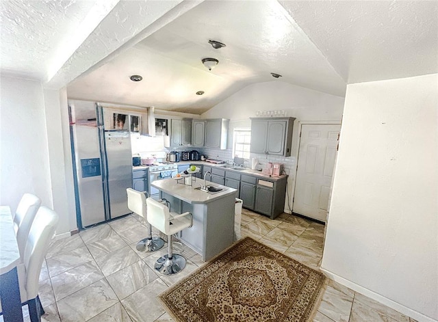 209 SW 40th St, Oklahoma City, OK 73109 - kitchen with stainless steel fridge, white range with gas cooktop, gray cabinets, lofted ceiling, and a kitchen island with sink