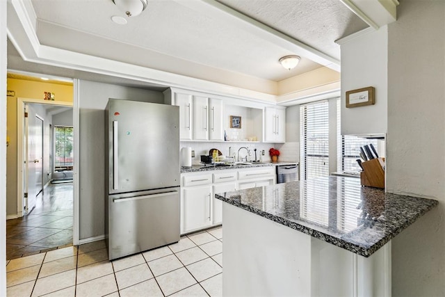 kitchen with appliances with stainless steel finishes, white cabinets, light tile patterned flooring, and a peninsula