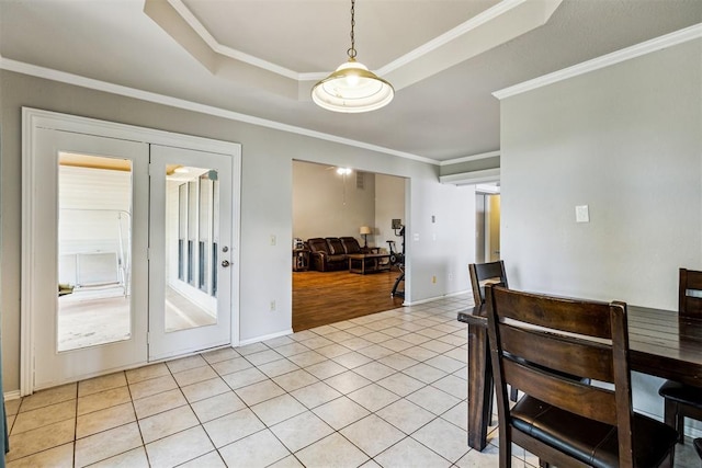 dining space featuring light tile patterned floors, crown molding, a tray ceiling, and baseboards