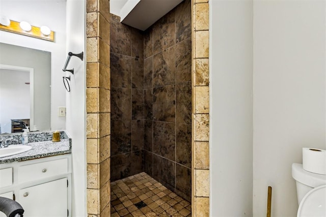full bath with a tile shower, vanity, and toilet