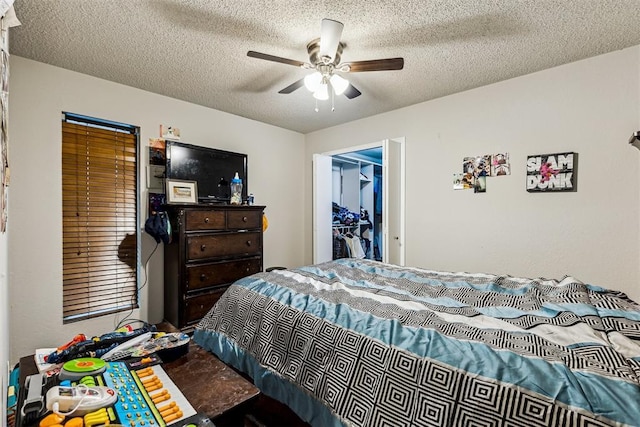 bedroom with a textured ceiling, a spacious closet, a ceiling fan, and a closet