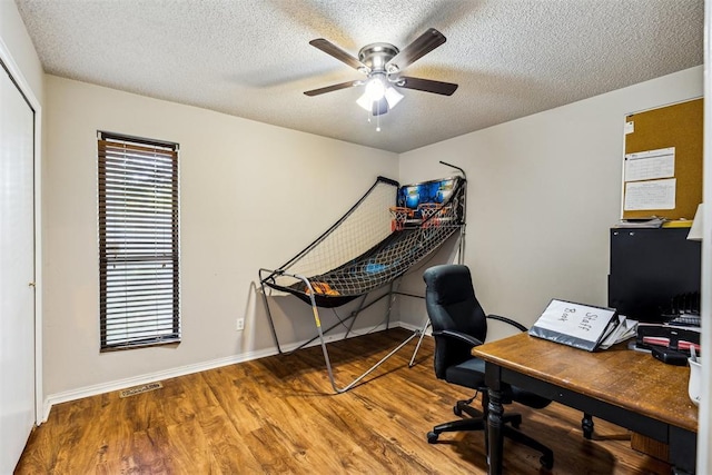 home office with a ceiling fan, wood finished floors, a textured ceiling, and baseboards
