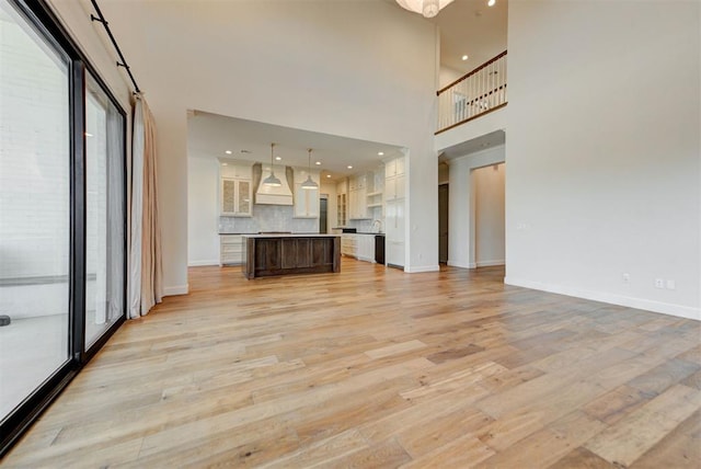 4209 Las Colinas Ln, Norman, OK 73072 - unfurnished living room with a high ceiling, light wood finished floors, baseboards, a sink, and recessed lighting