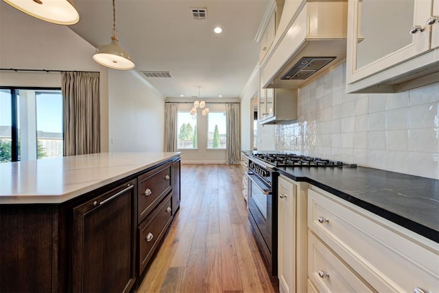 4209 Las Colinas Ln, Norman, OK 73072 - kitchen with high end range, custom exhaust hood, dark brown cabinetry, glass insert cabinets, and backsplash