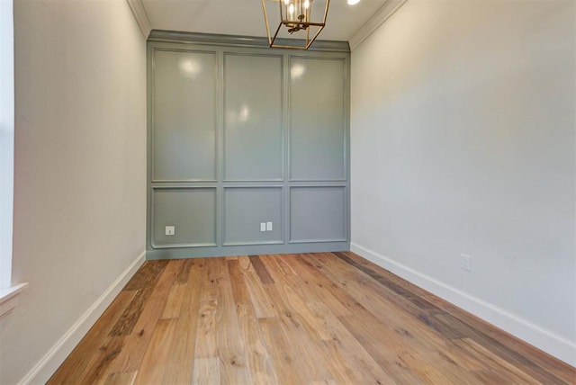 4209 Las Colinas Ln, Norman, OK 73072 - spare room featuring a chandelier, a decorative wall, wood finished floors, baseboards, and crown molding