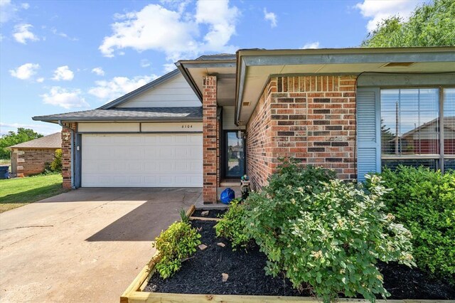 6104 Westlane, Oklahoma City, OK 73142 - view of front of property with brick siding, an attached garage, and concrete driveway