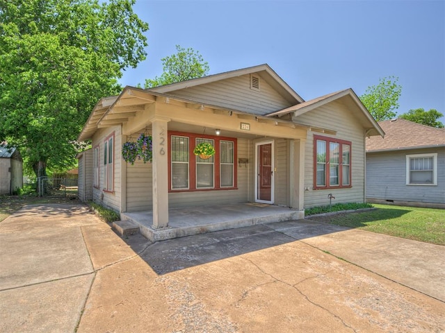 bungalow-style home with concrete driveway, a porch, and fence