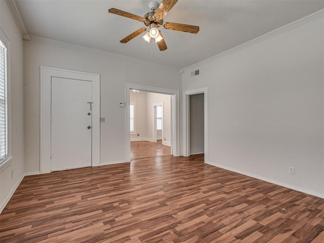 spare room with wood finished floors, ornamental molding, a ceiling fan, and baseboards