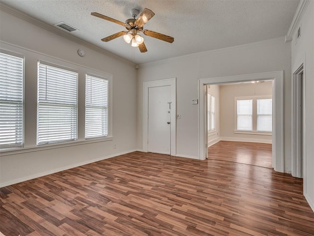 empty room with wood finished floors, ceiling fan, a textured ceiling, crown molding, and baseboards