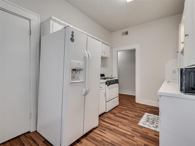 kitchen with white appliances, white cabinetry, wood finished floors, light countertops, and baseboards