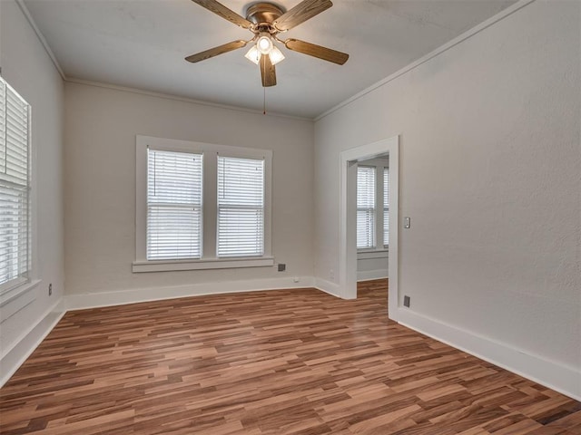 empty room featuring ornamental molding, a ceiling fan, wood finished floors, and baseboards