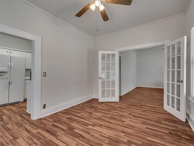spare room with french doors, ornamental molding, a ceiling fan, wood finished floors, and baseboards