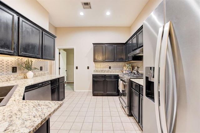 619 Rimrock Rd, Edmond, OK 73034 - kitchen featuring stainless steel appliances, light tile patterned floors, tasteful backsplash, under cabinet range hood, and light stone counters