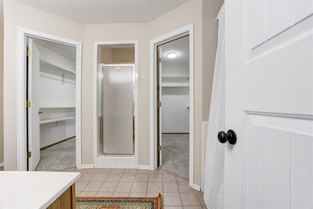 619 Rimrock Rd, Edmond, OK 73034 - bathroom featuring a shower stall, a spacious closet, vanity, tile patterned floors, and a textured ceiling
