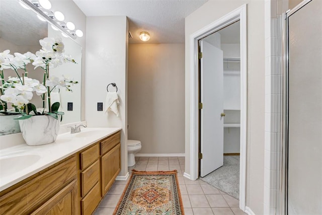 619 Rimrock Rd, Edmond, OK 73034 - bathroom with a spacious closet, double vanity, toilet, tile patterned flooring, and a shower with door