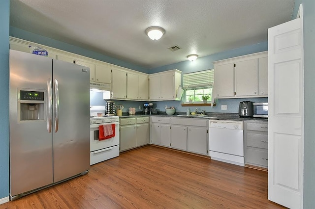 109 E Hayes St, Norman, OK 73069 - kitchen featuring white appliances, dark countertops, a sink, and wood finished floors