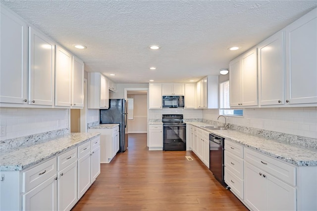 5016 NW 26th St, Oklahoma City, OK 73127 - kitchen with black appliances, decorative backsplash, wood finished floors, white cabinetry, and a textured ceiling