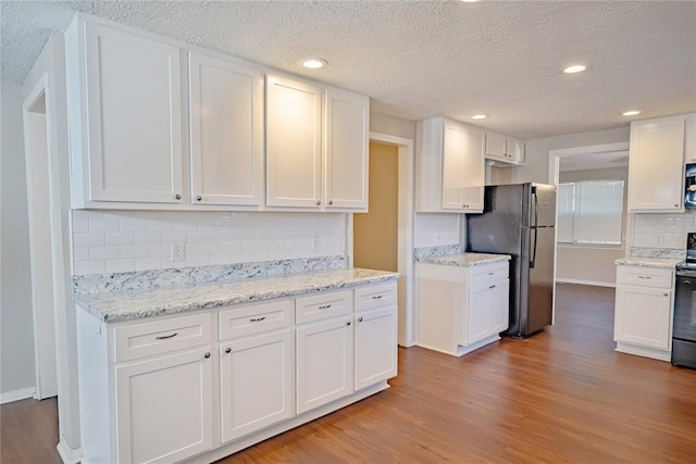 5016 NW 26th St, Oklahoma City, OK 73127 - kitchen featuring freestanding refrigerator, white cabinetry, wood finished floors, decorative backsplash, and electric range