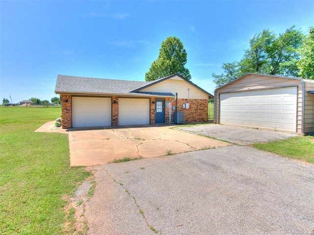 764 S Sara Rd, Tuttle, OK 73089 - view of front of home featuring a front lawn, central AC unit, brick siding, an outbuilding, and a garage