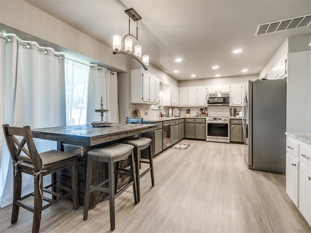 764 S Sara Rd, Tuttle, OK 73089 - kitchen featuring stainless steel appliances, light wood-style floors, decorative backsplash, a sink, and white cabinets