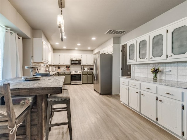 764 S Sara Rd, Tuttle, OK 73089 - kitchen with appliances with stainless steel finishes, light wood-style flooring, tasteful backsplash, white cabinets, and recessed lighting