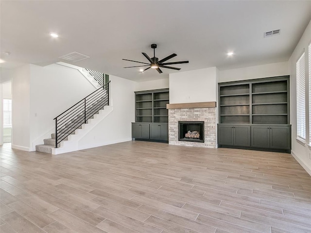 4405 Las Colinas Ln, Norman, OK 73072 - unfurnished living room with baseboards, stairway, ceiling fan, light wood-style floors, and a fireplace