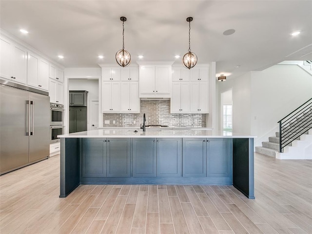 4405 Las Colinas Ln, Norman, OK 73072 - kitchen with stainless steel appliances, light countertops, light wood-type flooring, white cabinetry, and recessed lighting