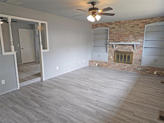 6805 Saint Marys Cir, Oklahoma City, OK 73132 - unfurnished living room featuring a ceiling fan, wood finished floors, built in shelves, baseboards, and a textured ceiling