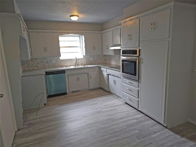 6805 Saint Marys Cir, Oklahoma City, OK 73132 - kitchen featuring dishwashing machine, oven, a sink, a textured ceiling, and tasteful backsplash