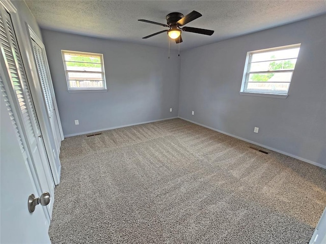 6805 Saint Marys Cir, Oklahoma City, OK 73132 - unfurnished bedroom with carpet floors, multiple windows, a textured ceiling, baseboards, and a ceiling fan