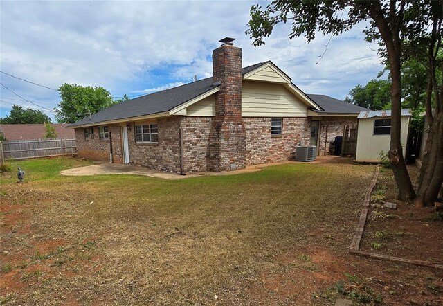 6805 Saint Marys Cir, Oklahoma City, OK 73132 - rear view of property with a chimney, central AC unit, brick siding, an outdoor structure, and a patio
